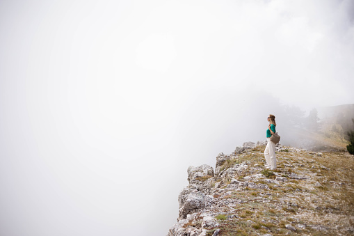 Girl tourist enjoys a beautiful view of the fog in the mountains.