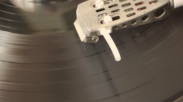 Close up view of dusty needle of old record player with spinning vinyl record.