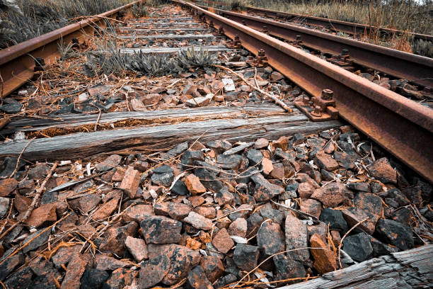 Weathered railway tracks and new rusty metal rails laying on a bed of gravel and ballast