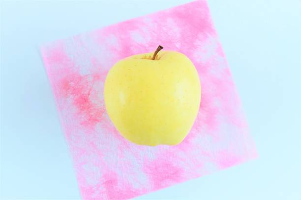 istock A single yellow apple placed on pink Japanese paper against a white background 1471446508