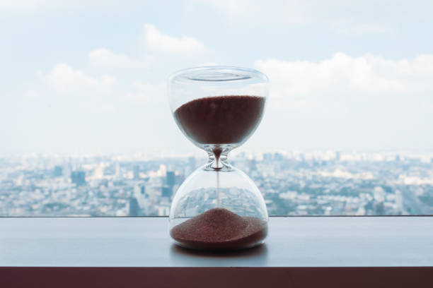 Hourglass with cityscape on panoramic skyline and buildings in the morning background with sun light. The concept of modern life, business, time, management and city life. stock photo