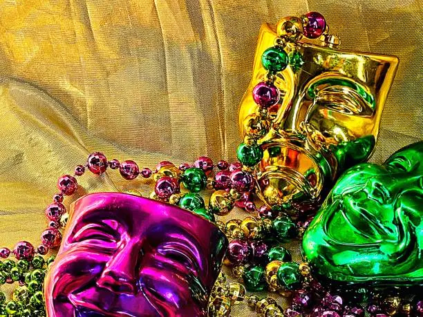 Traditional Mardi Gras masks and beads, vibrant symbolic colors against gold lame backdrop with space for copy. Green purple gold justice faith power.