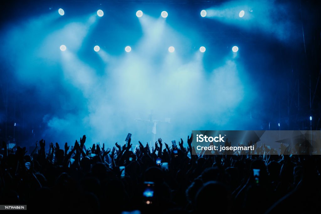Crowd of people dancing at a music show in Barcelona during the summer of 2022 Crowd of people dancing at a music show in Barcelona in blue colour during the summer of 2022 Music Festival Stock Photo