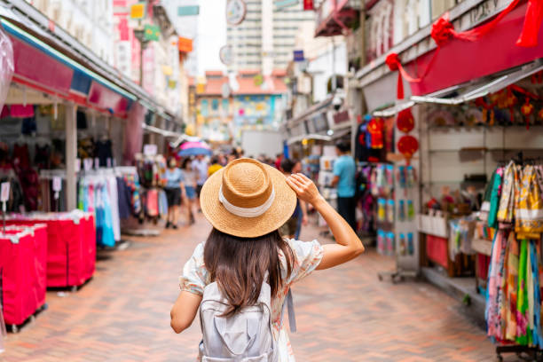Young female tourist walking in Chinatown street market in Singapore Young female tourist walking in Chinatown street market in Singapore singapore holidays stock pictures, royalty-free photos & images