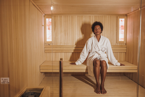 Beautiful mature African American woman relaxing in a sauna at the spa centre.