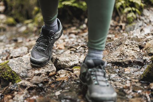 Cropped shot of an unrecognisable woman hiker crossing a stream while exploring in the woods.