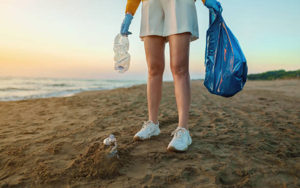 istock Woman volunteer collects garbage on the beach. Environmental pollution. 1471462811
