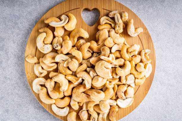 istock Cashew nuts on round wooden board and white background. 1471463195