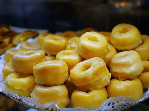 Close up selective focus Typical dessert Dough in Alcala style, Rosquillas de Alcala, puff pastry with yellow egg yolk coating with syrup, Ring shaped, donuts, in pastry shop