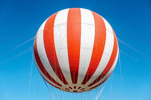Old fashioned helium balloon with red and white stripes on blue sky