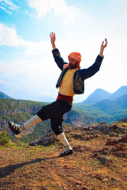 a man plays folk dance in local dress in nature.man playing the traditional dance zeybek.