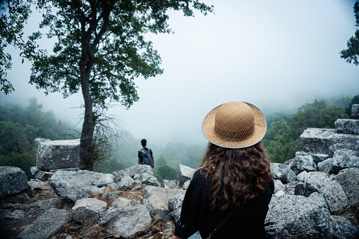 Man and woman in straw hats watching landscape in a foggy valley