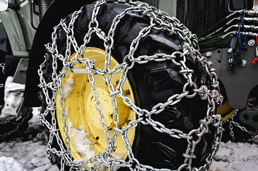 close up of a snowplow wheel with snow chains.