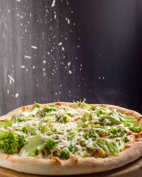 Ready pizza is sprinkled with cheese stock photo