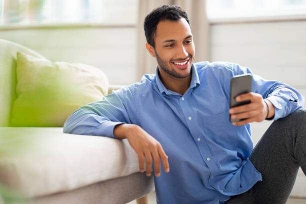 istock Portrait of smiling Arab man using smartphone at home 1471477817