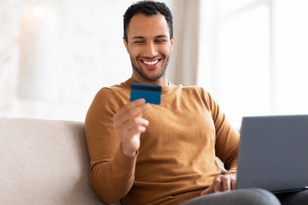 istock Casual smiling man using pc and credit card at home 1471477821