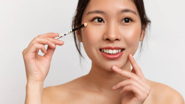 istock Pretty korean lady using cosmetic brush to apply nude eyeshadows, posing over white studio background, closeup 1471477968