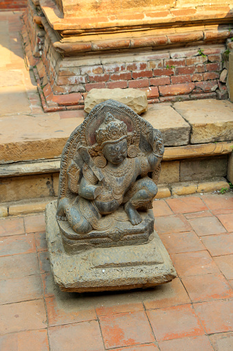 Small hindu God statue stands on street tiled floor on Patan Durbar Square in Lalitpur city, Nepal. Soft focus. Religious heritage theme.