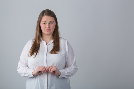 Studio portrait of good looking overweight female person posing with a serious expression