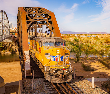 Yuma, AZ / USA - 02/21/2023: A shot of a Union Pacific locomotive while crossing a trestle over the Colorado river in Yuma, AZ.