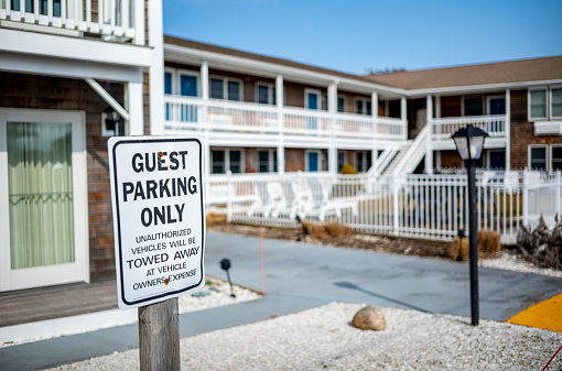 A image of a motel during the winter awaiting the busy summer tourist season.  A lonely parking sign stands in from of the empty motel rooms in Falmouth, MA, on Cape Cod in Massachusetts.