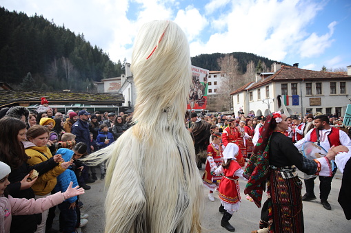 Shiroka laka, Bulgaria - March 5, 2023: People with mask called Kukeri dance and perform to scare the evil spirits at the Festival of the Masquerade Games \