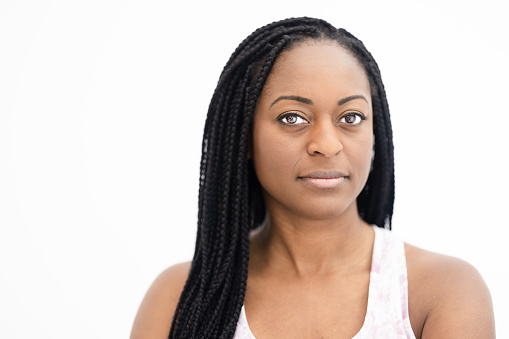 Portrait of a serious middle aged black woman on a white background, looking at the camera