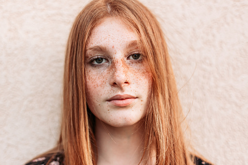 Close-up portrait of young teen freckled ginger girl looking away