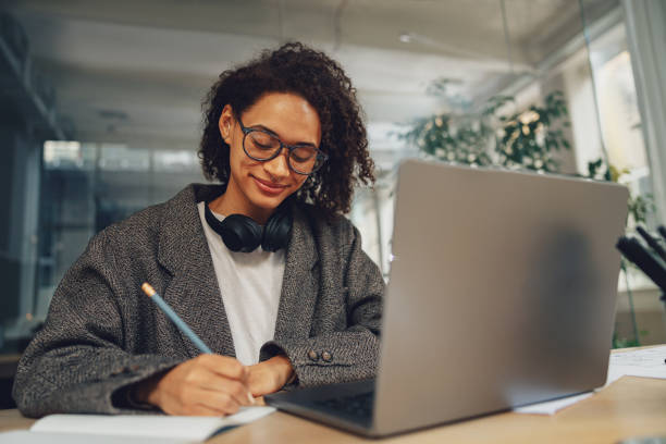 istock Woman office worker working on laptop and making notes while sitting in coworking 1471486420