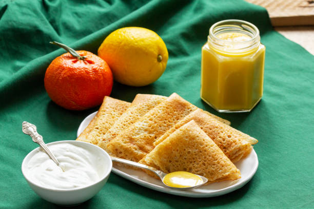 Pancakes served with fruit curd and sour cream, a traditional meal for Maslenitsa and Carnival.