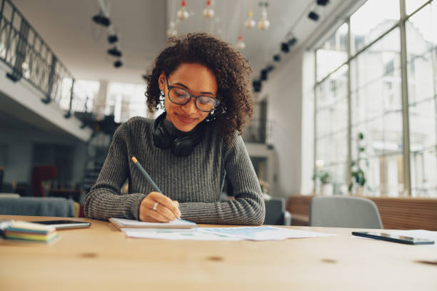 istock Attractive young female student studying and making notes in modern coworking 1471488294