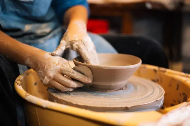 Close up on skillful hands making and sculpting pottery jar on potter wheel with tools and water in workshop, Creative and artwork, Handmade craft