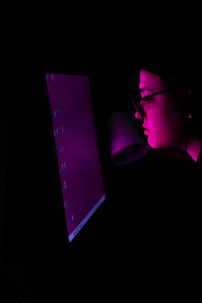 istock Girl with glasses watching a magenta computer screen. 1471491673