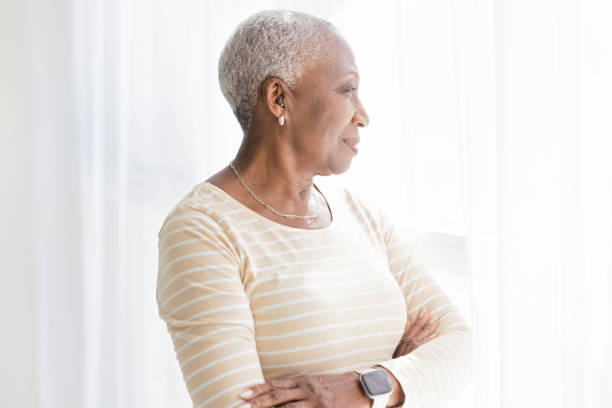 窓際で考える年配の黒人女性 - ipad senior adult 70s adult ストックフォトと画像
