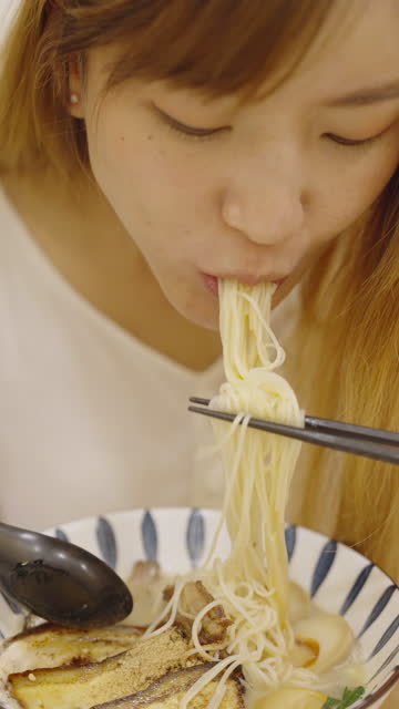 Hungry beautiful Asian woman eating Japanese noodle