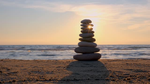 Balanced pebble pyramid silhouette on the beach