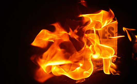 Printed media being consumed by fire.