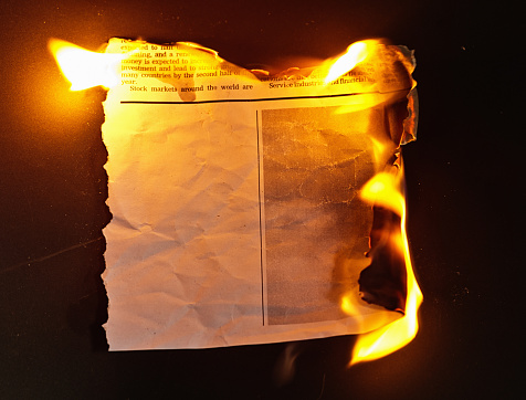 Burning piece of paper torn from a simulated newspaper, designed by the photographer and free of design copyright. Blank area in which to insert your copy.