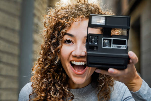 молодая женщина-фотограф делает мгновенные снимки старой винтажной камерой на открытом воздухе - творческий городской образ жизни - photographer women retro revival camera стоковые фото и изображения
