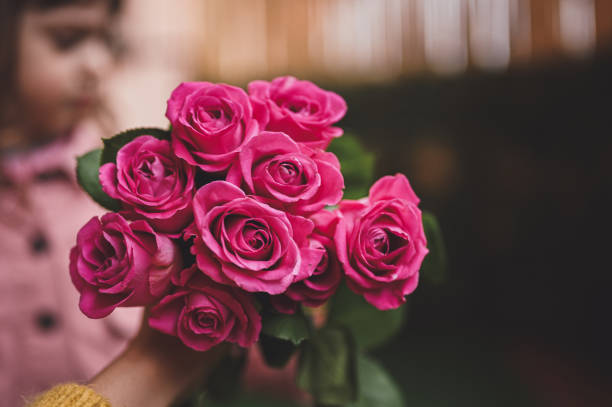 muttertagsgeschenk. mutter, die blumen von ihrer kleinen tochter hält. aufschließen. - rose family stock-fotos und bilder