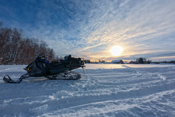 istock Snowmobile, helmet on snow field at forest side, sunset Sun, cloudy blue sky. Side view 1471507710