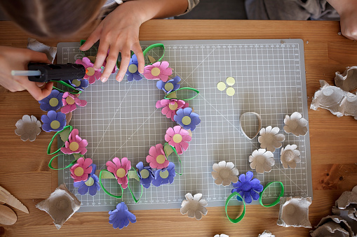 Transformation an ordinary egg carton into a beautiful Easter flower wreath. Kids show the creative and sustainable possibilities of Zero Waste lifestyle. Reduce, reuse, and recycle. DIY with kids