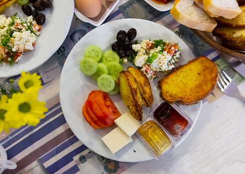 Traditional halal breakfast including cheese, olives, toasted bread, baked potatoes and fresh vegetables served in Turkish hotel