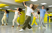 Group of teenagers in casual clothes training hip hop in class, posing and having fun