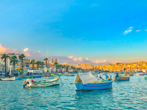 Marsaxlokk, Malta - November, 2018: Boats in the harbour of Marsaxlokk, picture taken from the waterfront.