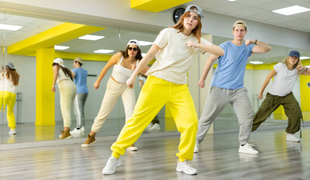 Group of young teen boy and girls dancing in spacious hall with mirrors. The concept of sport, dance and healthy lifestyle Diligent sporty teenagers performing dynamic energetic dancing movements in modern loft studio k pop stock pictures, royalty-free photos & images