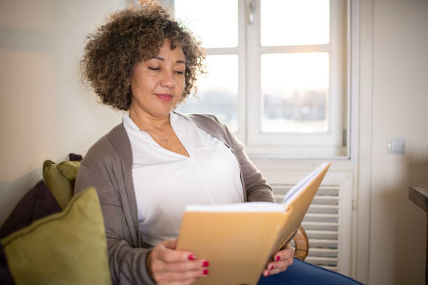 istock Woman reading book at home 1471518309