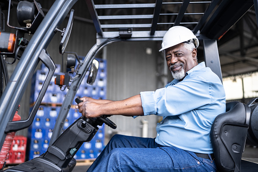 Portrait of a senior man in a forklift in a warehouse