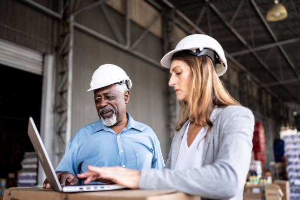 istock Coworkers talking and using the laptop in a warehouse 1471519044