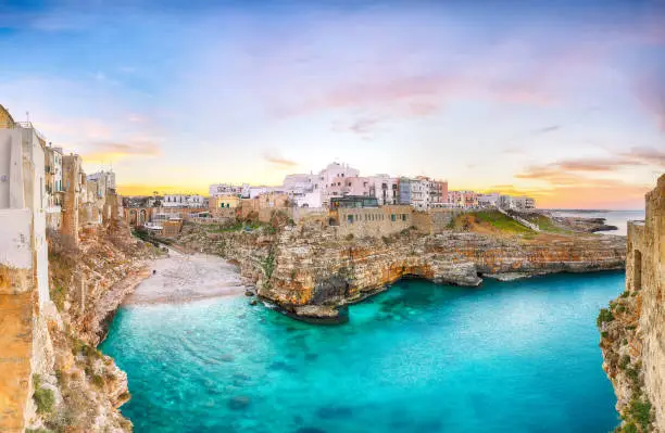 Stunning sunset at Cala Paura gulf with Bastione di Santo Stefano and Lama Monachile beach in background. Polignano a Mare, Apulia, Italy, province of Bari.